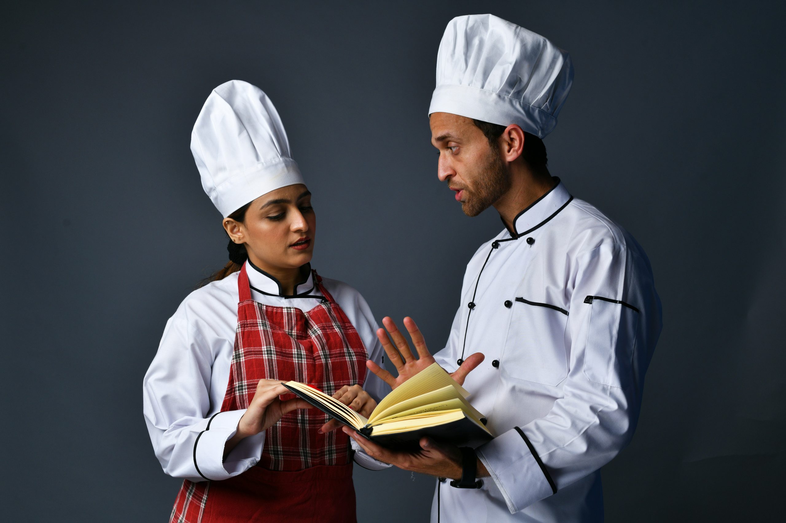chef teaching another chef something from a book. Photo by Fotos on Unsplash